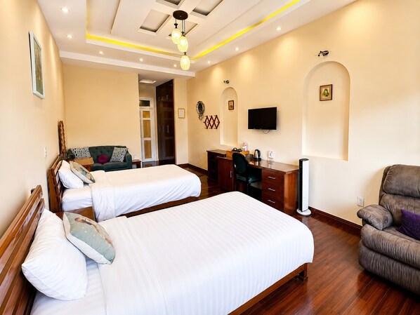 A hotel room with two beds, a desk, a chair, a TV, and a wardrobe.
