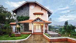 A two-story house with a stone facade, a tiled roof, and a front porch with a railing. - Terrasse Des Roses (Lang Biang - Da Lat)