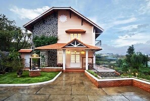 A two-story house with a stone facade, a tiled roof, and a front porch with a railing. - Terrasse Des Roses (Da Lat)