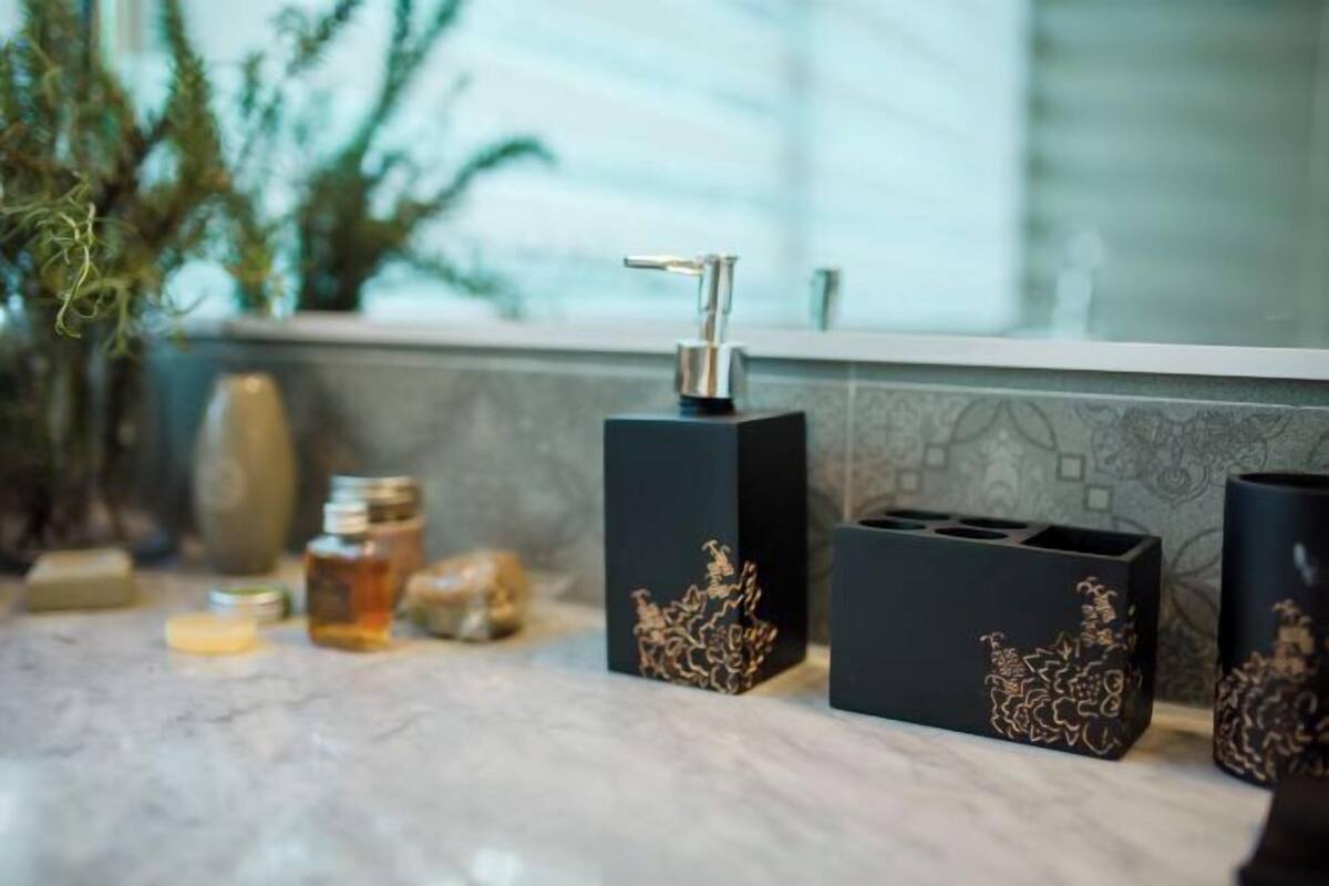 A bathroom with a marble countertop, a black soap dispenser, and decorative vases.