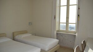 Ein Zimmer mit zwei Betten, einem Fenster mit Blick und einer Marmorwand.
