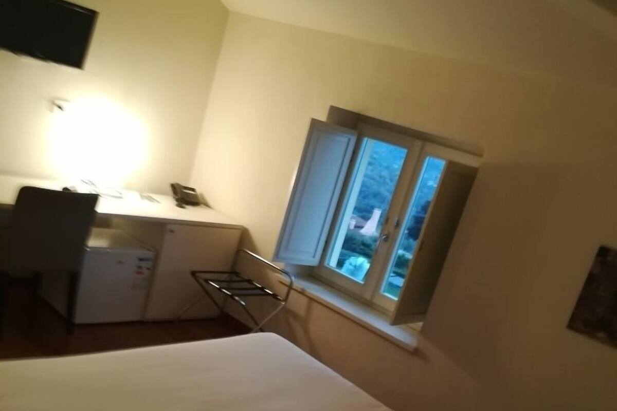 Un dormitorio con cama, escritorio y ventana.