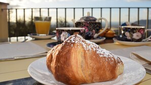 Ein Croissant auf einem Teller, im Hintergrund eine Teekanne und Tassen.