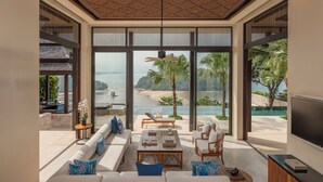 Una sala de estar moderna con un amplio ventanal, una piscina y vistas a la playa.
