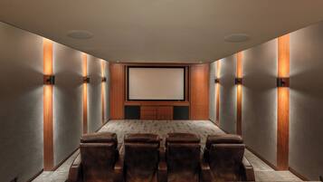 Un salón de conferencias con una pantalla grande, sillas de cuero y detalles de madera.