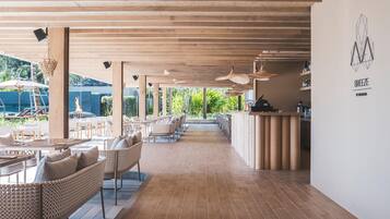 A spacious outdoor seating area with wicker furniture, a bar, and a view of a pool and greenery.
