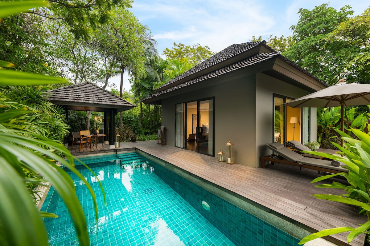 A modern house with a swimming pool, wooden deck, and lounge chairs.