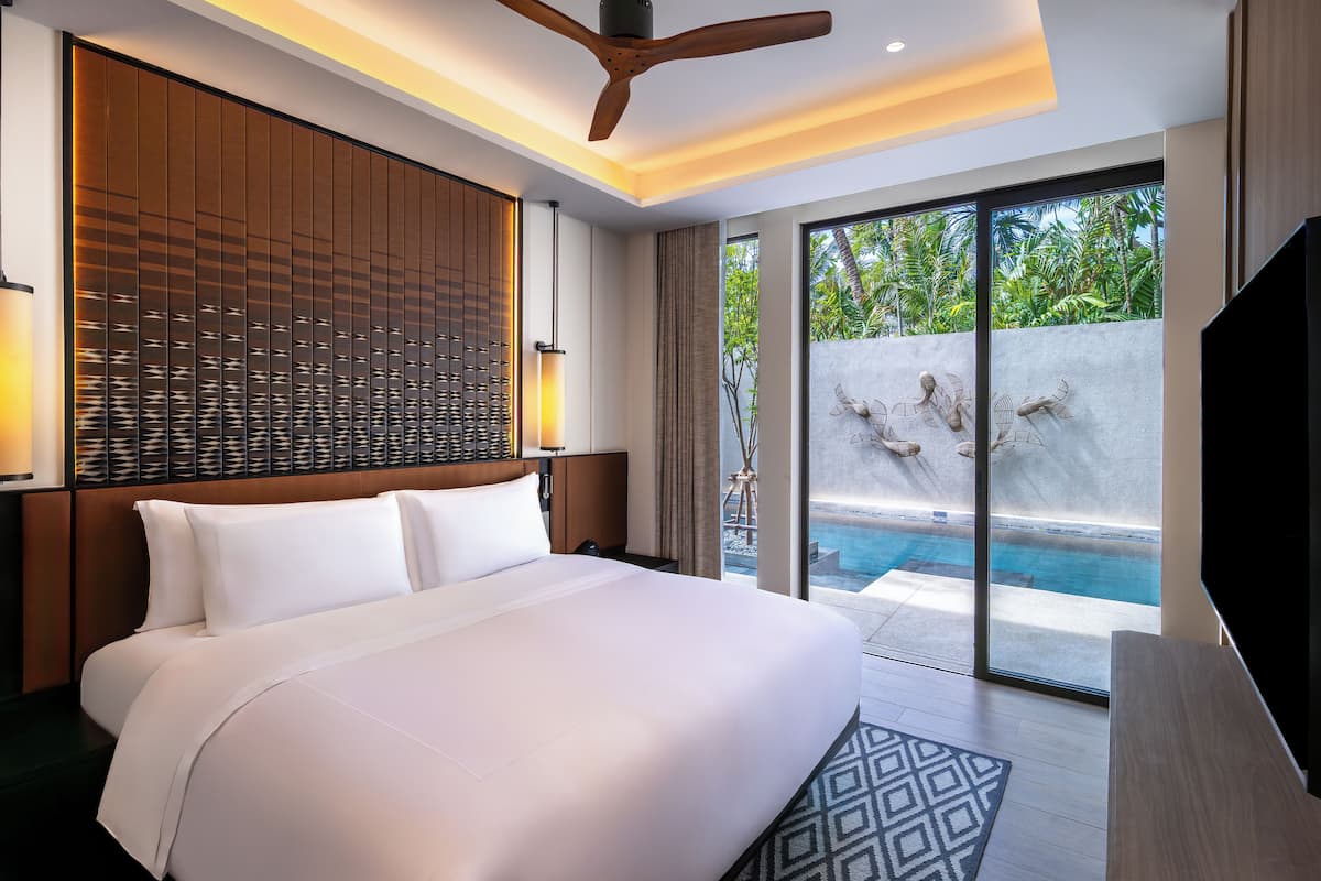 A modern hotel room with a large bed, a ceiling fan, a view of a swimming pool, and a large TV.