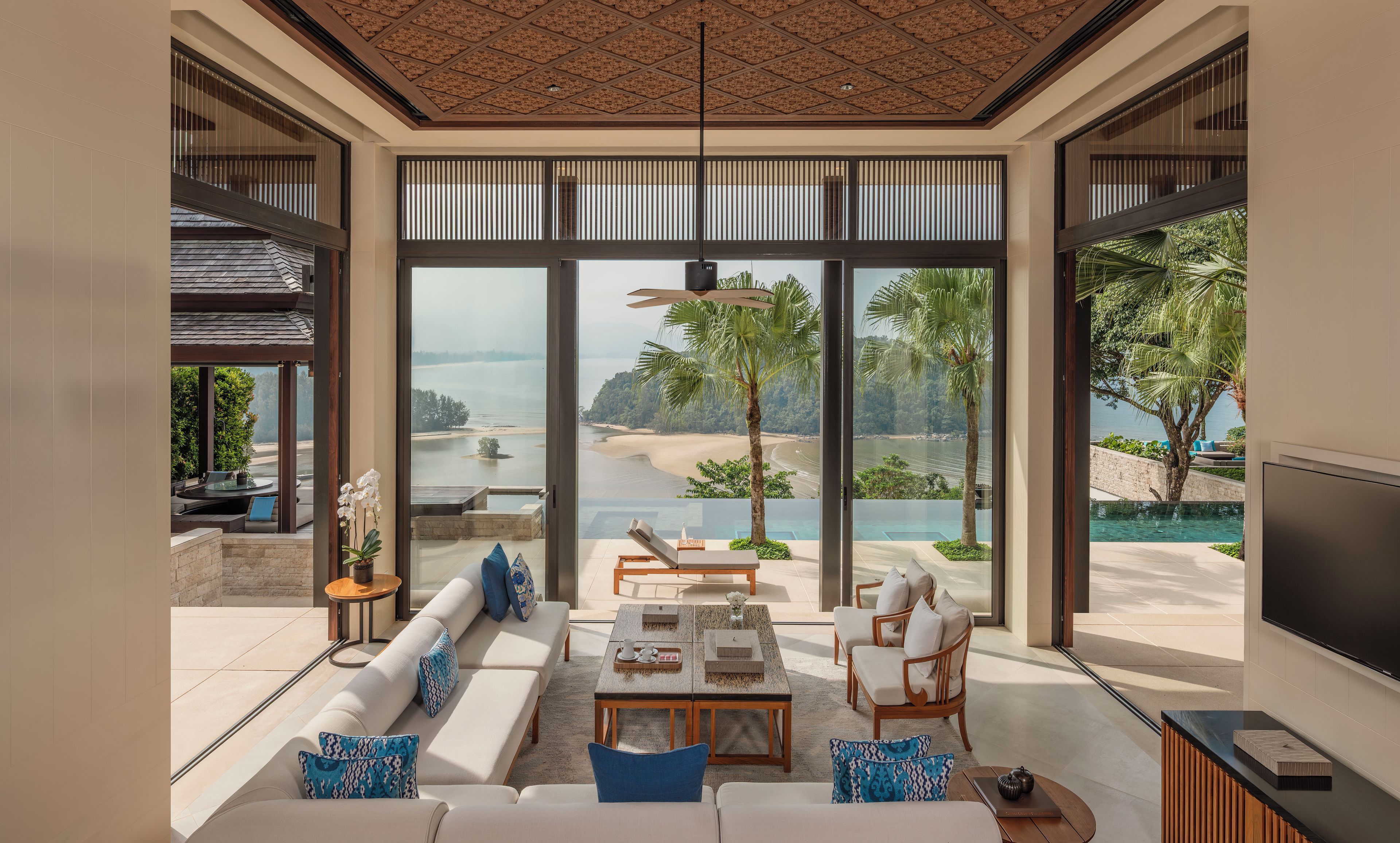 Una sala de estar moderna con un amplio ventanal, una piscina y vistas a la playa.