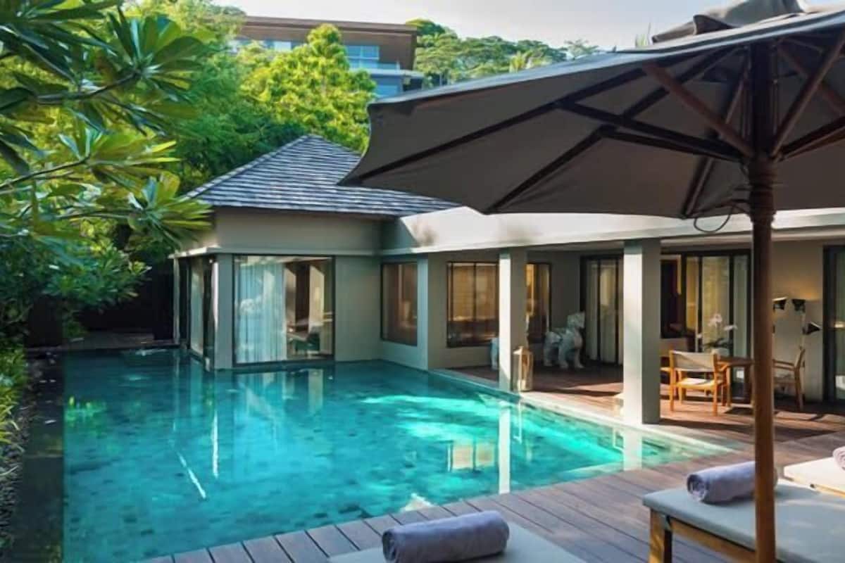 A modern pool area with a clear pool, wooden deck, and lounge chairs.