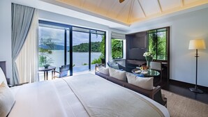 Un dormitorio amplio con una cama grande, una zona de estar con una mesa y vistas a un lago.