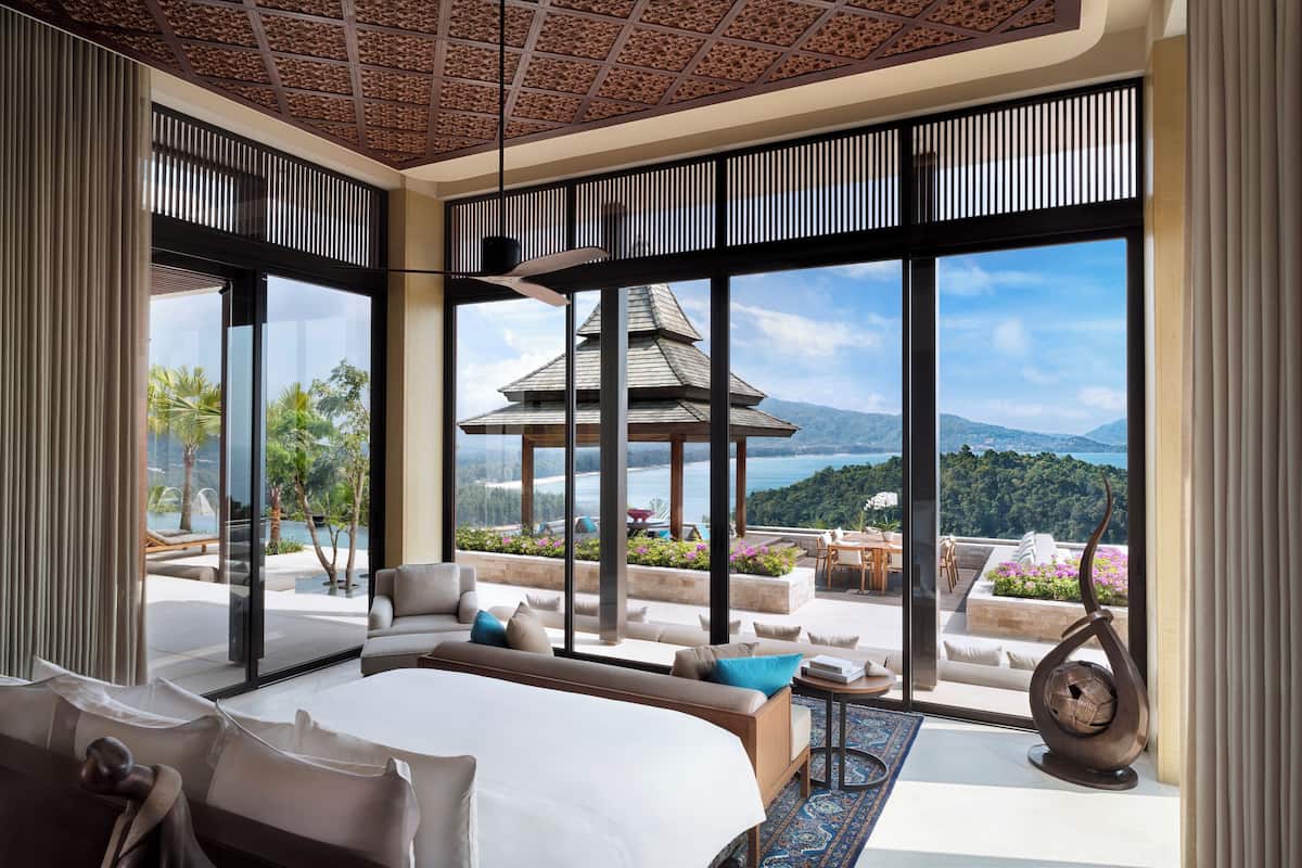 A spacious bedroom with a large bed, a sofa, and a view of a traditional pagoda and mountains.