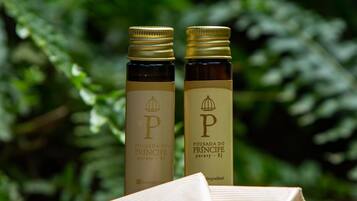 Two bottles with labels and a booklet on a surface with greenery in the background.