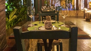 An indoor dining area with tables set for two, featuring woven ceiling and walls, and a view of greenery outside. - Pousada do Principe (Paraty)