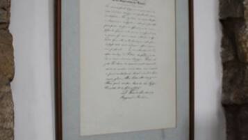 Un documento enmarcado en una pared, sobre un fondo de pared de piedra.