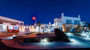 A modern building with a white facade, arched windows, and a large rock in the foreground. - Kouros Home Hotel (Rhodes)