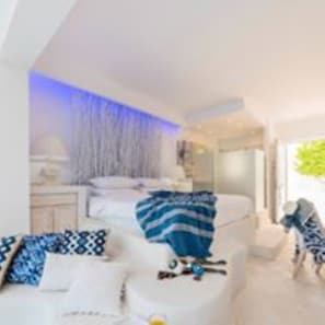Quarto moderno com cama, mesa de cabeceira e apoio para objetos pessoais.