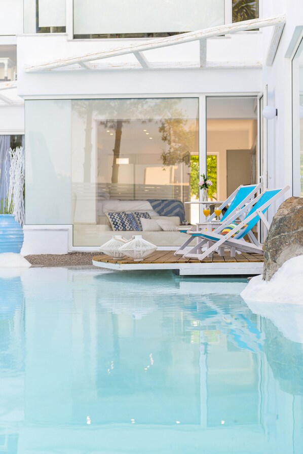 Ein moderner Poolbereich im Freien mit Liegestühlen und einer patioartigen Glasveranda.