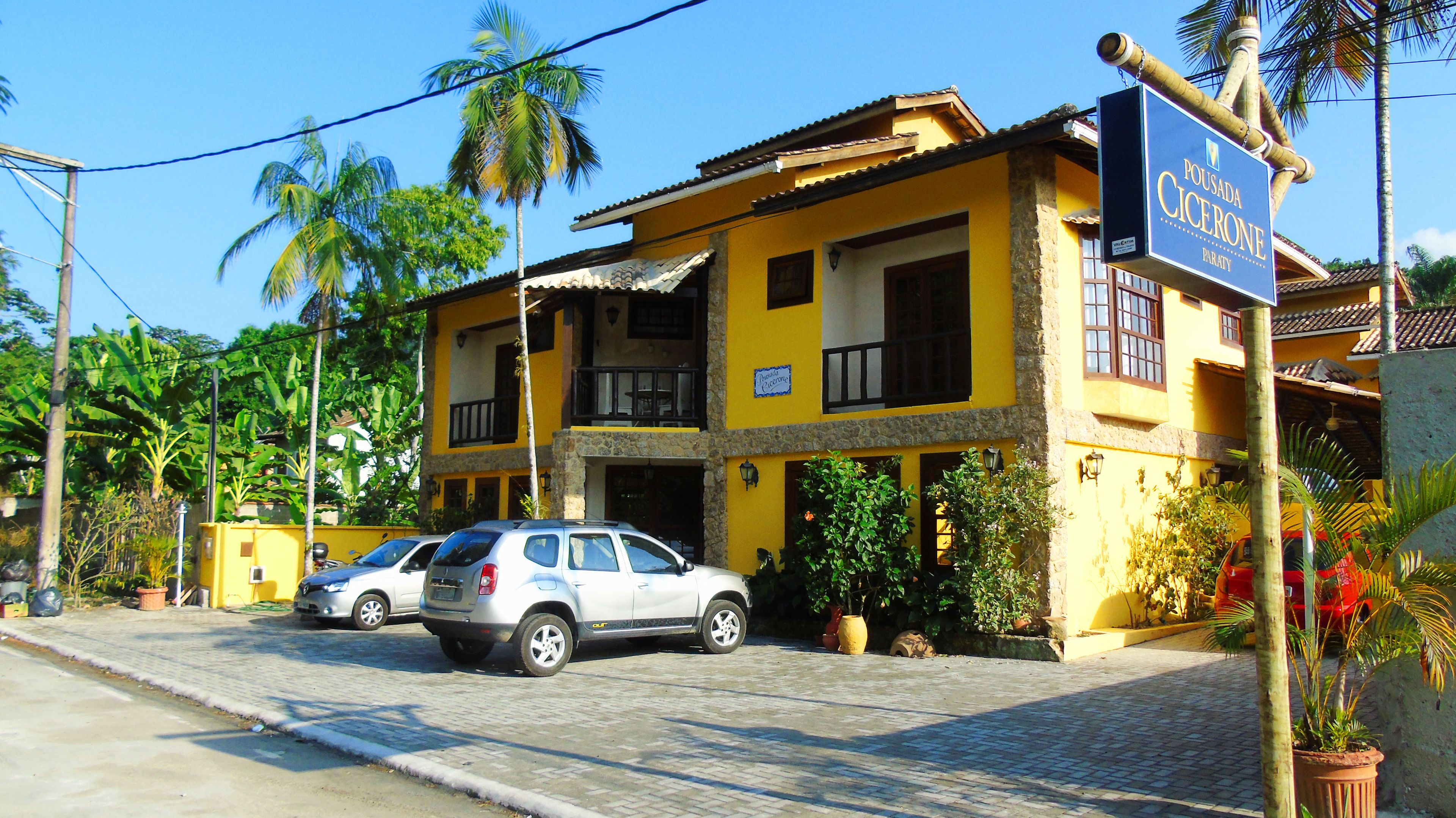 A two-story building with a yellow facade, a balcony, and a sign for Pousada Cicerone.
