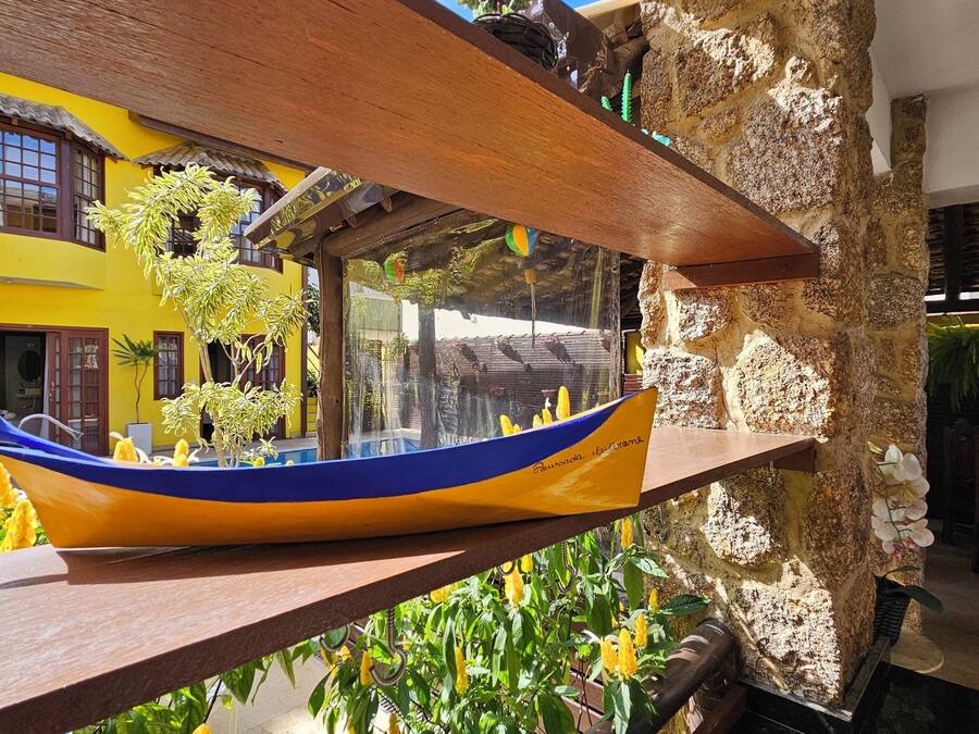 A wooden boat model, a stone wall, and a yellow building with windows.