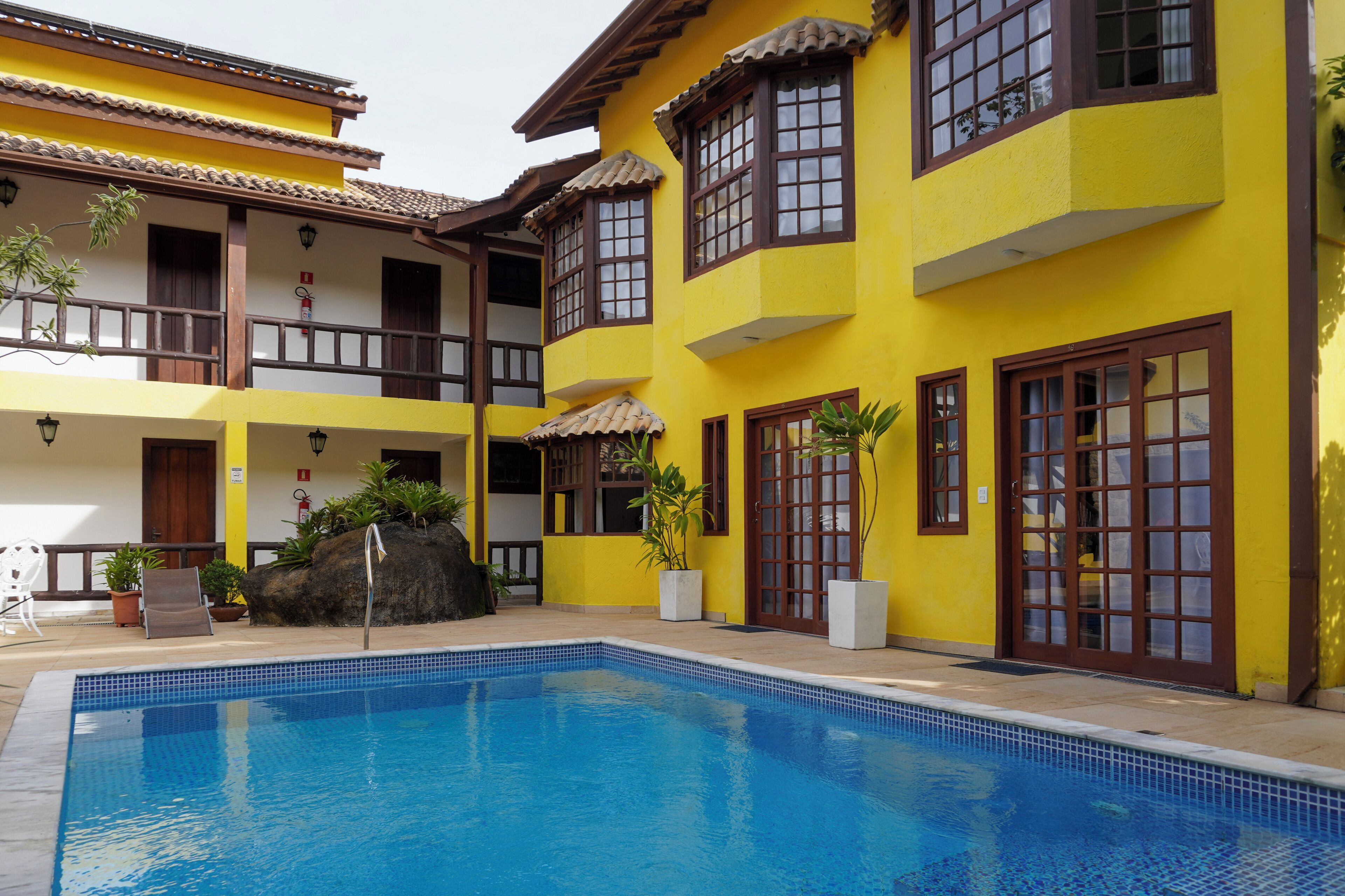 Un bâtiment jaune doté d’une piscine, de balcons et de plantes en pot.