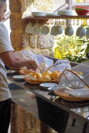 Un'area buffet con cesti di cibo, un espositore di bicchieri appeso e una parete in pietra sullo sfondo.