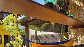Un barco modelo sobre una estantería de madera, rodeado de plantas verdes y flores amarillas.