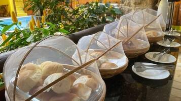 Montaje de buffet con cuencos tapados de pan y utensilios.