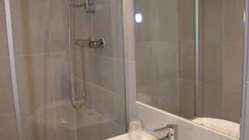 Een moderne badkamer met een douche met glazen wand, een witte wastafel en een grote spiegel.