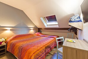 A bedroom with two beds, a desk, a chair, a small table with a vase of flowers, and a skylight. - Alb'hotel Grill (Alby-sur-Cheran)