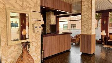 Un'area di accoglienza con una scrivania in legno, un vaso grande e una parete decorata.
