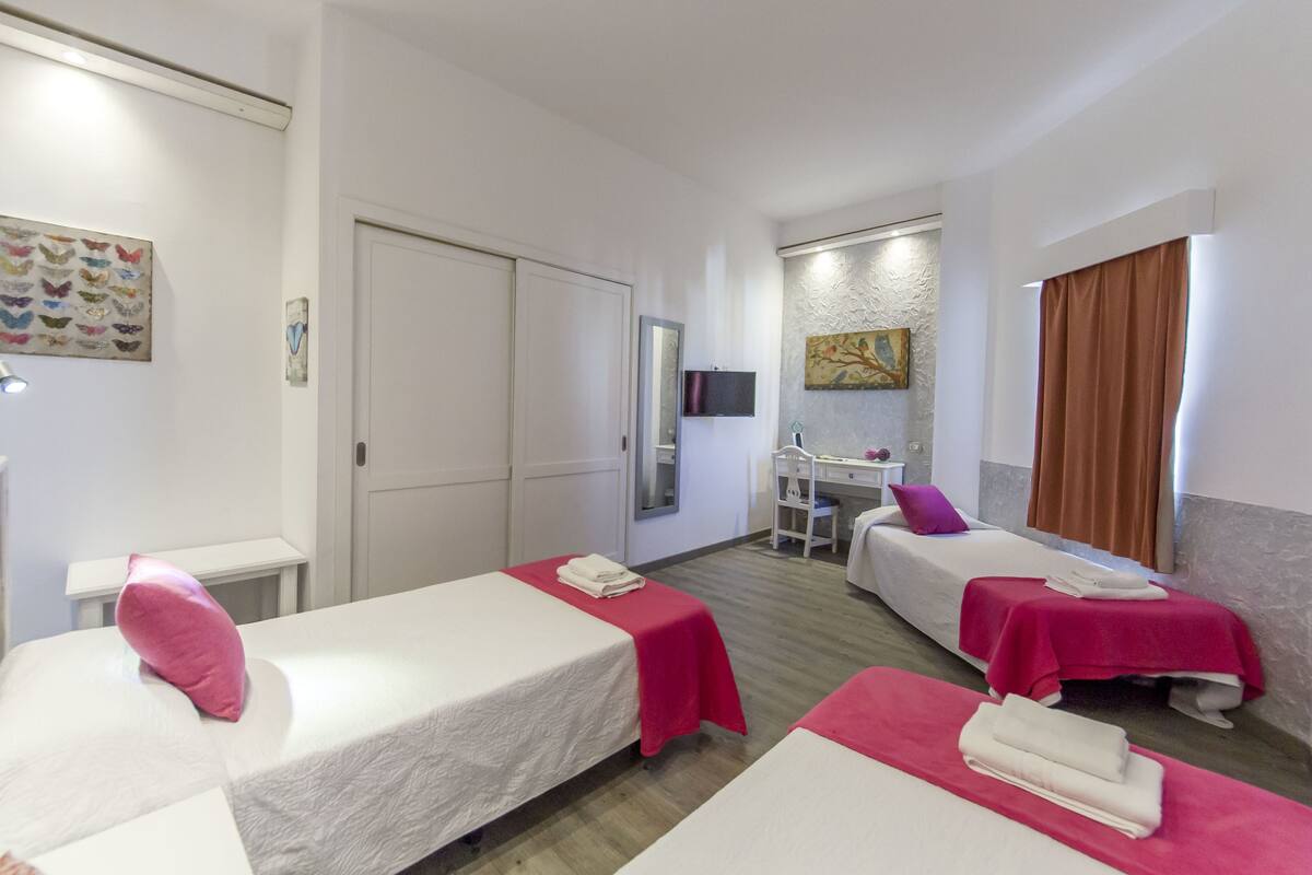 Quarto de hotel com duas camas, uma escrivaninha e uma cadeira.