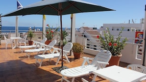 A terrace with white lounge chairs and a table, overlooking the sea. - Hotel Sun Holidays (Puerto de la Cruz)