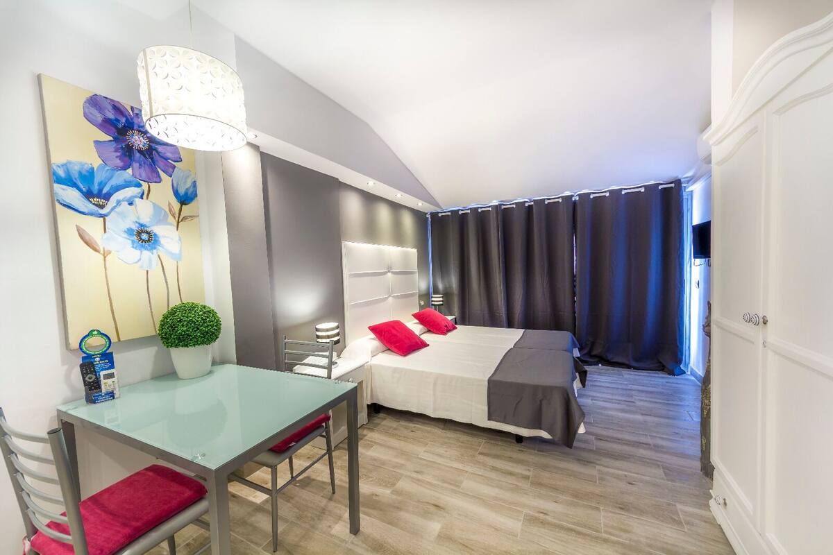 Quarto moderno com cama, mesa de cabeceira e escrivaninha com cadeira.