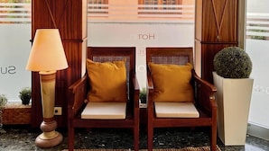 A reception area with two wooden chairs with cushions, a lamp, and a potted plant. - Hotel Sun Holidays (Puerto de la Cruz)