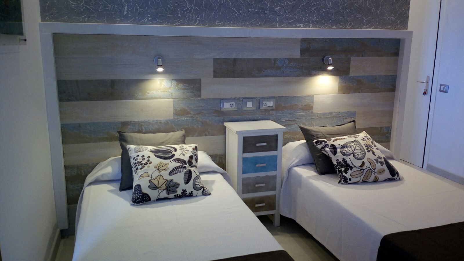 Un dormitorio con dos camas, cada una con una almohada y una mesita de noche.