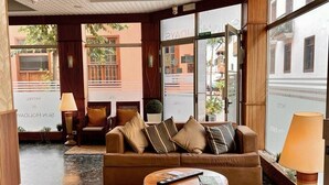 A lobby with a brown leather sofa, a round wooden coffee table, and a lamp. - Hotel Sun Holidays (Puerto de la Cruz)