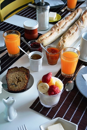 Ein Frühstückstisch mit Brot, Obst und Saft.