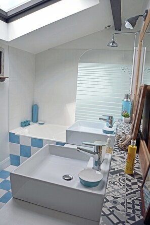 Ein modernes Badezimmer mit einer großen Badewanne, einem separaten Waschbecken und einer Duschkabine.