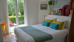 A bedroom with a large bed, a chair, and a view of the outdoors.