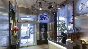 A hotel reception area with a glass door entrance, a reception desk, and a seating area. - Hôtel de Paris (Lyon)