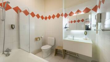 Une salle de bain avec douche, toilettes et lavabo.