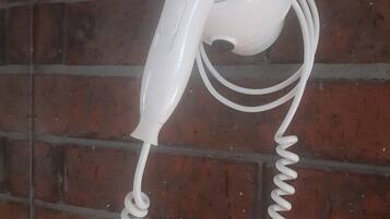 A white hair dryer mounted on a brick wall.