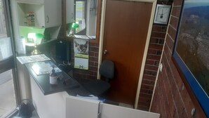 A small office with a desk, chair, and a door. There is a window with a view of the outside, a clock on the wall, and a calendar on the door. - City Gardens Motel Traralgon (Traralgon)