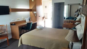 Une chambre d’hôtel comprenant un lit, un bureau, une chaise et une salle de bain avec un lavabo et un miroir.