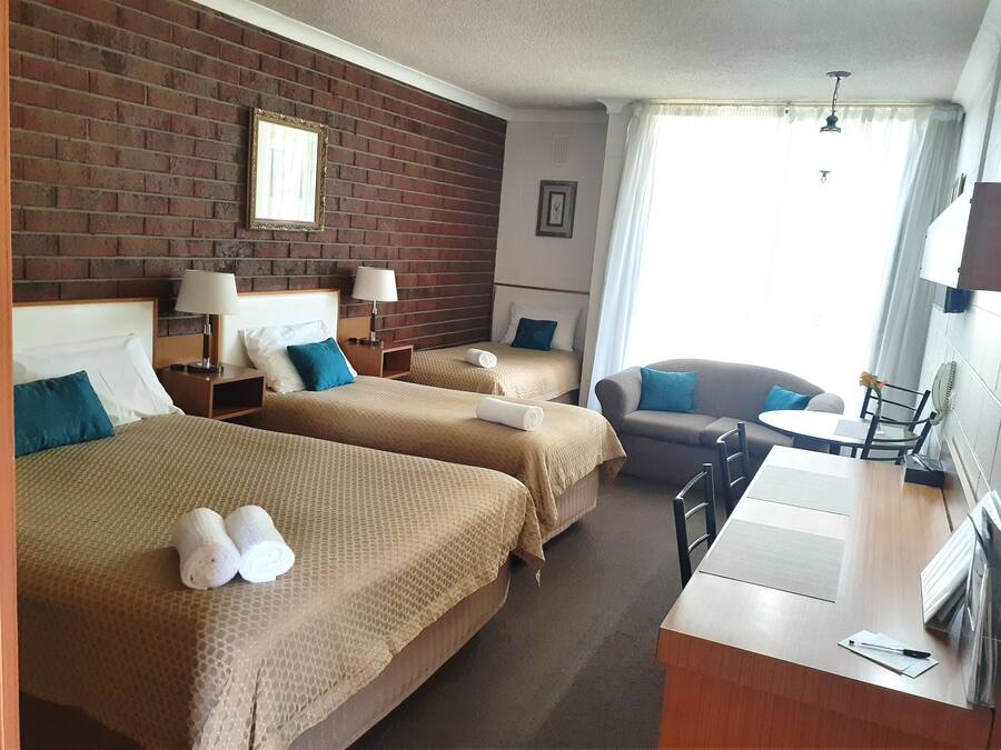 Une chambre d’hôtel avec deux lits, un canapé, une petite table et un bureau.
