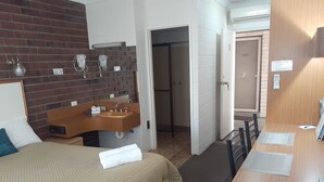 A hotel room with a bed, a wooden vanity with a sink, a mirror, and a door leading to a bathroom. - City Gardens Motel Traralgon (Traralgon)