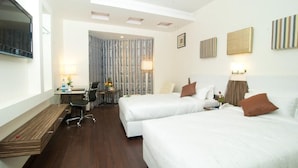 A hotel room with two beds, a desk, a chair, and a TV. - Hotel Ambica Sea Green (Visakhapatnam)