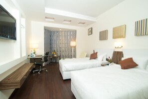 Une chambre d’hôtel avec deux lits, un bureau, une chaise et un téléviseur.