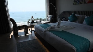 A hotel room with a bed, a view of the ocean, a chair, and a table with a lamp. - Hotel Ambica Sea Green (Visakhapatnam)